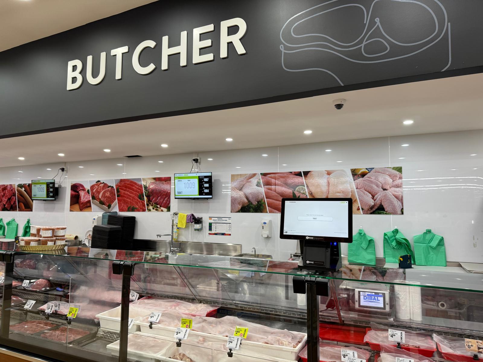 QRight touchscreen ticket kiosk and wall-mounted queue displays at the FoodWorks butcher counter